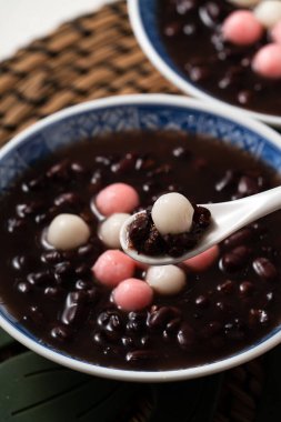 Kırmızı ve beyaz tangyuan 'a (tang yuan, glutinous rice dumpling balls) kışın gündönümü festivali için beyaz masa arkasındaki tatlı kırmızı fasulye çorbasıyla yakın çekim yapın..