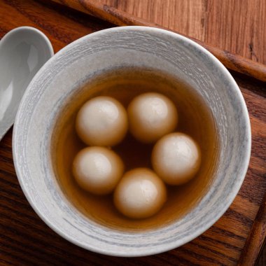 Büyük susam tangyuan 'ın (tang yuan, glutinous rice dumpling balls) en üst görüntüsü. Kış gündönümü festivali için ahşap masa arkasındaki tatlı şurup çorbası..