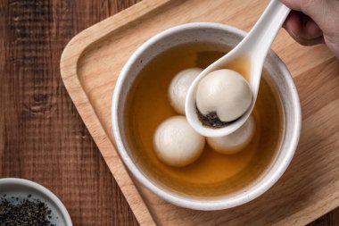Büyük susam tangyuan 'ın (tang yuan, glutinous rice dumpling balls) en üst görüntüsü. Kış gündönümü festivali için ahşap masa arkasındaki tatlı şurup çorbası..