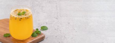 Gri masa arkaplanında köpüklü meyve suyu olan lezzetli taze tutku meyvelerini yakın plan..