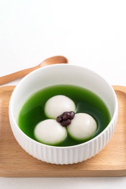 Matcha Big Tangyuan 'ı (tang yuan) tatlı kibrit çorbası ve kırmızı fasulye ezmesi ile festival yemeği için beyaz masa arkasında bir kaseye yakın çekim yapın..