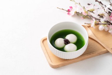 Matcha Big Tangyuan 'ı (tang yuan) tatlı kibrit çorbası ve kırmızı fasulye ezmesi ile festival yemeği için beyaz masa arkasında bir kaseye yakın çekim yapın..