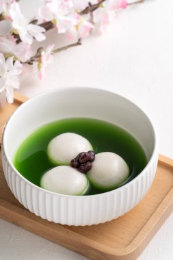 Matcha Big Tangyuan 'ı (tang yuan) tatlı kibrit çorbası ve kırmızı fasulye ezmesi ile festival yemeği için beyaz masa arkasında bir kaseye yakın çekim yapın..