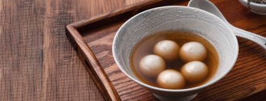 Susam büyük tangyuan (tang yuan, glutinous rice dumpling balls) yakın çekim Tahta masa üzerinde tatlı şurup çorbası ile Kış gündönümü festivali için.
