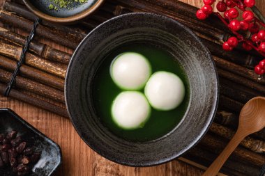 Matcha Büyük Tangyuan 'ın (tang yuan) en üst görüntüsü, festival yemekleri için ahşap masa arkasındaki tatlı kibrit çorbası kasesinde..