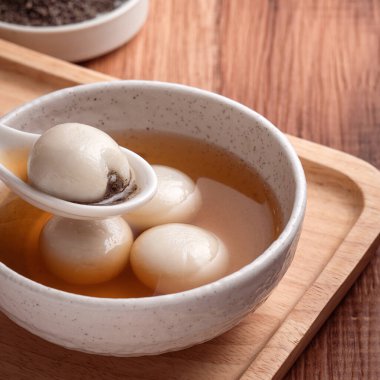 Susam büyük tangyuan (tang yuan, glutinous rice dumpling balls) yakın çekim Tahta masa üzerinde tatlı şurup çorbası ile Kış gündönümü festivali için.