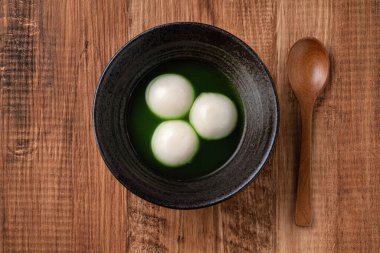 Matcha Büyük Tangyuan 'ın (tang yuan) en üst görüntüsü, festival yemekleri için ahşap masa arkasındaki tatlı kibrit çorbası kasesinde..