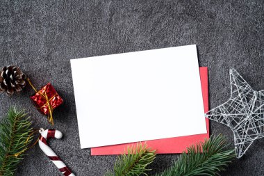 Köknar ağacı dalı, kar tanesi, çam kozalağı ve boş kart içeren Noel arkaplan tasarımı kavramının en üst görünümü.