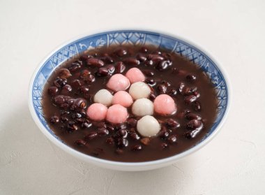 Kırmızı ve beyaz tangyuan 'a (tang yuan, glutinous rice dumpling balls) kışın gündönümü festivali için beyaz masa arkasındaki tatlı kırmızı fasulye çorbasıyla yakın çekim yapın..