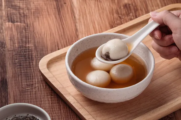 Susam büyük tangyuan (tang yuan, glutinous rice dumpling balls) yakın çekim Tahta masa üzerinde tatlı şurup çorbası ile Kış gündönümü festivali için.