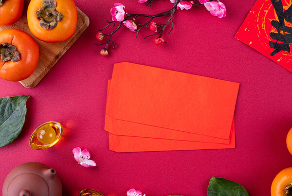 Top view of fresh sweet persimmons kaki with leaves on red table background for Chinese lunar new year fruit design concept, the word means spring is coming.