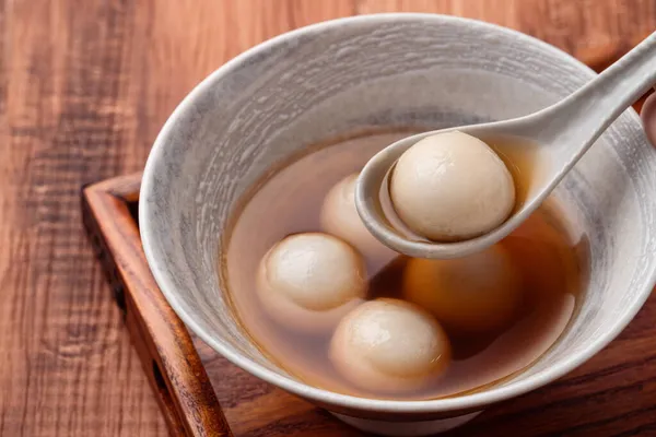 Susam büyük tangyuan (tang yuan, glutinous rice dumpling balls) yakın çekim Tahta masa üzerinde tatlı şurup çorbası ile Kış gündönümü festivali için.