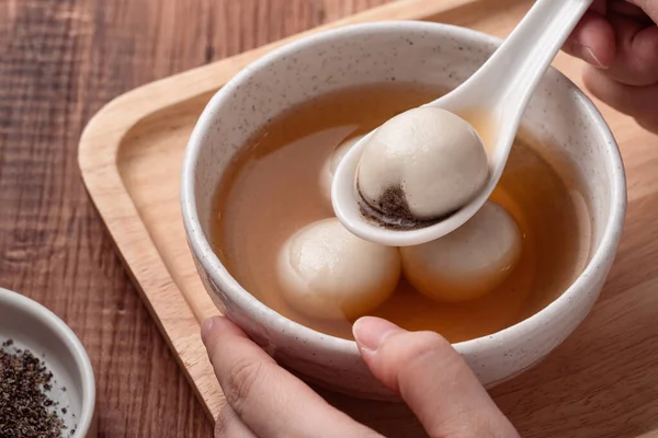 Susam büyük tangyuan (tang yuan, glutinous rice dumpling balls) yakın çekim Tahta masa üzerinde tatlı şurup çorbası ile Kış gündönümü festivali için.