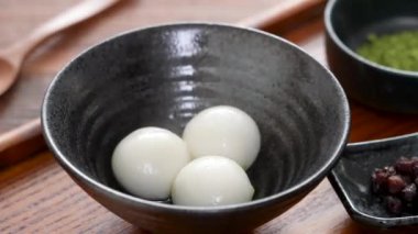 Matcha büyük tangyuan 'ı (tang yuan) tatlı kibrit çorbası ve kırmızı fasulye ezmesi ile beyaz masa arkasında festival yemeği için hazırlamaya yakın durun..