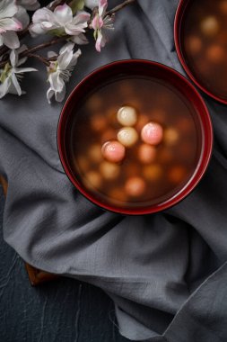 Kırmızı ve beyaz tangyuan 'ın (tang yuan, glutinous rice dumpling balls) en üst görüntüsü. Kış gündönümü festivali için mavi masa arkasındaki tatlı şurup çorbası..