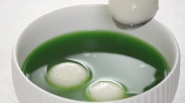 Matcha büyük tangyuan 'ı (tang yuan) tatlı kibrit çorbası ve kırmızı fasulye ezmesi ile beyaz masa arkasında festival yemeği için hazırlamaya yakın durun..