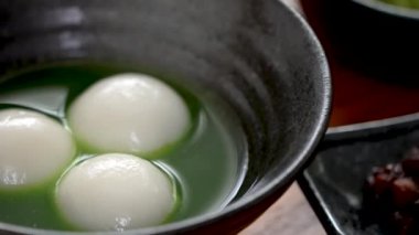 Matcha büyük tangyuan 'ı (tang yuan) tatlı kibrit çorbası ve kırmızı fasulye ezmesi ile beyaz masa arkasında festival yemeği için hazırlamaya yakın durun..