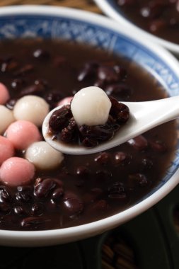Kırmızı ve beyaz tangyuan 'a (tang yuan, glutinous rice dumpling balls) kışın gündönümü festivali için beyaz masa arkasındaki tatlı kırmızı fasulye çorbasıyla yakın çekim yapın..