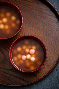 Kırmızı ve beyaz tangyuan 'ın (tang yuan, glutinous rice dumpling balls) en üst görüntüsü. Kış gündönümü festivali için mavi masa arkasındaki tatlı şurup çorbası..