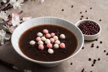 Kırmızı ve beyaz tangyuan 'a (tang yuan, glutinous rice dumpling balls) Gri masa üzerinde tatlı kırmızı fasulye çorbası ile kış gündönümü festivali yemeği için.