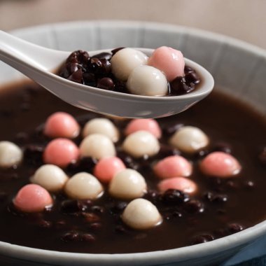 Kırmızı ve beyaz tangyuan 'a (tang yuan, glutinous rice dumpling balls) Gri masa üzerinde tatlı kırmızı fasulye çorbası ile kış gündönümü festivali yemeği için.