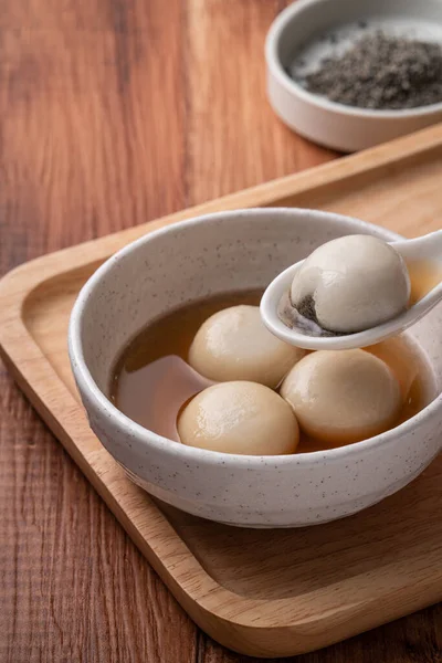 Susam büyük tangyuan (tang yuan, glutinous rice dumpling balls) yakın çekim Tahta masa üzerinde tatlı şurup çorbası ile Kış gündönümü festivali için.