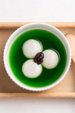 Matcha büyük tangyuan 'ın (tang yuan) beyaz masa arkasında tatlı kibrit çorbası ve kırmızı fasulye ezmesi ile festival yemeği için beyaz masa arkasında.