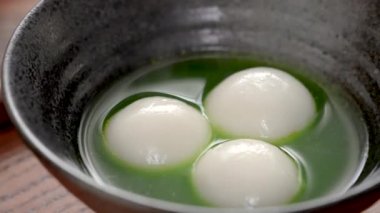  Matcha büyük tangyuan 'ı (tang yuan) tatlı kibrit çorbası ve kırmızı fasulye ezmesi ile beyaz masa arkasında festival yemeği için hazırlamaya yakın durun..