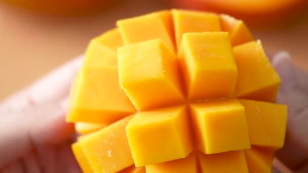 女性は新鮮なマンゴーの果物を切断し 食べるための家庭のキッチンでダイスされたパルプのジューシーな側面を示しています — ストック動画