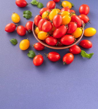 Taze kiraz domatesleri ahşap bir kasede mavi arka planda izole edilmiş, yakın plan, boşluğu kopyala