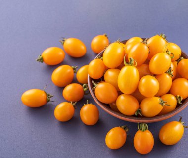 Taze kiraz domatesleri ahşap bir kasede mavi arka planda izole edilmiş, yakın plan, boşluğu kopyala