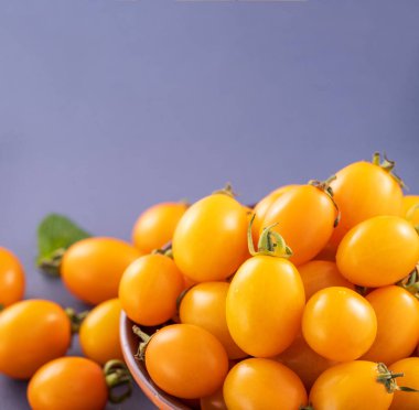 Taze kiraz domatesleri ahşap bir kasede mavi arka planda izole edilmiş, yakın plan, boşluğu kopyala