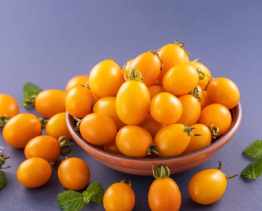 Taze kiraz domatesleri ahşap bir kasede mavi arka planda izole edilmiş, yakın plan, boşluğu kopyala