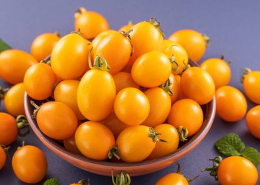 Taze kiraz domatesleri ahşap bir kasede mavi arka planda izole edilmiş, yakın plan, boşluğu kopyala