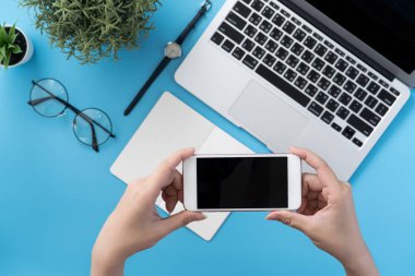 Ofis masası kavramını moda aksesuarlarına bağlayan sosyal ağ, akıllı telefon tutan bir kadınla minimum iç mekan, üst görünüm, düz mekan, taklit alanı