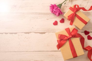 Kırmızı kurdele ve karanfilli Kraft hediye kutusu. Anneler gününde hediye verme konsepti. Sürpriz, düz yatak, üst manzara.