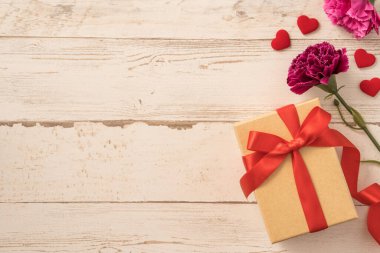 Kırmızı kurdele ve karanfilli Kraft hediye kutusu. Anneler gününde hediye verme konsepti. Sürpriz, düz yatak, üst manzara.