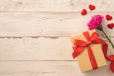 Kırmızı kurdele ve karanfilli Kraft hediye kutusu. Anneler gününde hediye verme konsepti. Sürpriz, düz yatak, üst manzara.