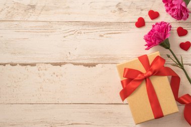 Kırmızı kurdele ve karanfilli Kraft hediye kutusu. Anneler gününde hediye verme konsepti. Sürpriz, düz yatak, üst manzara.