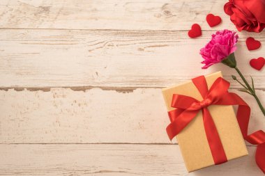 Kırmızı kurdele ve karanfilli Kraft hediye kutusu. Anneler gününde hediye verme konsepti. Sürpriz, düz yatak, üst manzara.