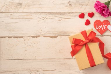 Kırmızı kurdele ve karanfilli Kraft hediye kutusu. Anneler gününde hediye verme konsepti. Sürpriz, düz yatak, üst manzara.