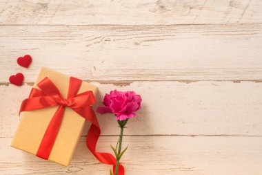 Kırmızı kurdele ve karanfilli Kraft hediye kutusu. Anneler gününde hediye verme konsepti. Sürpriz, düz yatak, üst manzara.