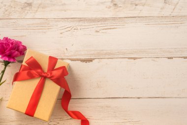 Kırmızı kurdele ve karanfilli Kraft hediye kutusu. Anneler gününde hediye verme konsepti. Sürpriz, düz yatak, üst manzara.