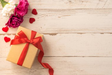 Kırmızı kurdele ve karanfilli Kraft hediye kutusu. Anneler gününde hediye verme konsepti. Sürpriz, düz yatak, üst manzara.