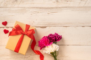 Kırmızı kurdele ve karanfilli Kraft hediye kutusu. Anneler gününde hediye verme konsepti. Sürpriz, düz yatak, üst manzara.