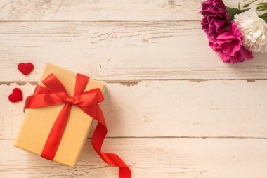 Kırmızı kurdele ve karanfilli Kraft hediye kutusu. Anneler gününde hediye verme konsepti. Sürpriz, düz yatak, üst manzara.