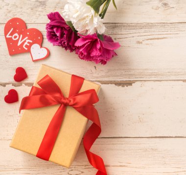 Kırmızı kurdele ve karanfilli Kraft hediye kutusu. Anneler gününde hediye verme konsepti. Sürpriz, düz yatak, üst manzara.