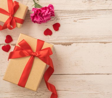 Kırmızı kurdele ve karanfilli Kraft hediye kutusu. Anneler gününde hediye verme konsepti. Sürpriz, düz yatak, üst manzara.