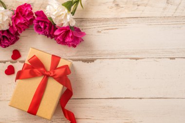 Kırmızı kurdele ve karanfilli Kraft hediye kutusu. Anneler gününde hediye verme konsepti. Sürpriz, düz yatak, üst manzara.