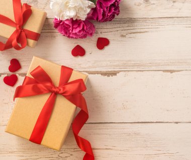 Kırmızı kurdele ve karanfilli Kraft hediye kutusu. Anneler gününde hediye verme konsepti. Sürpriz, düz yatak, üst manzara.